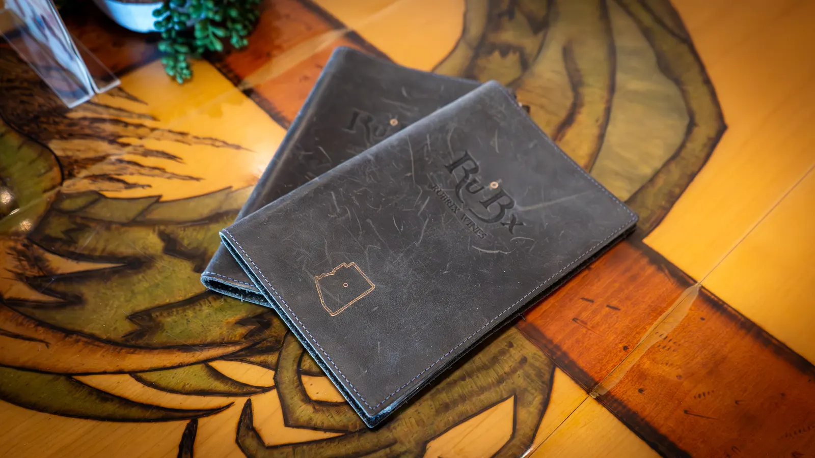 Ru°Bx branded leather menus on a carved wood table